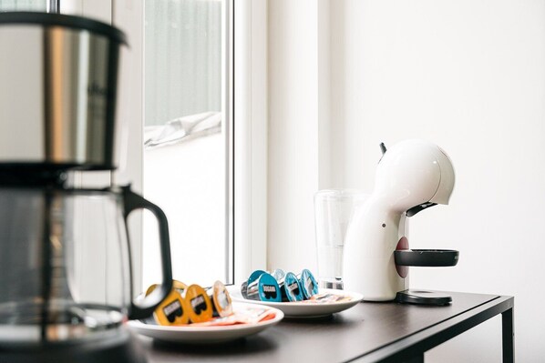 Una encimera de cocina con una cafetera, un secador de pelo y algunos alimentos envasados.