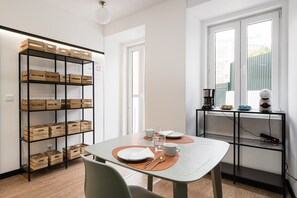 Enjoy meals in this dining area with a table set for a meal, a shelving unit for storage, and a cozy spot near the window.