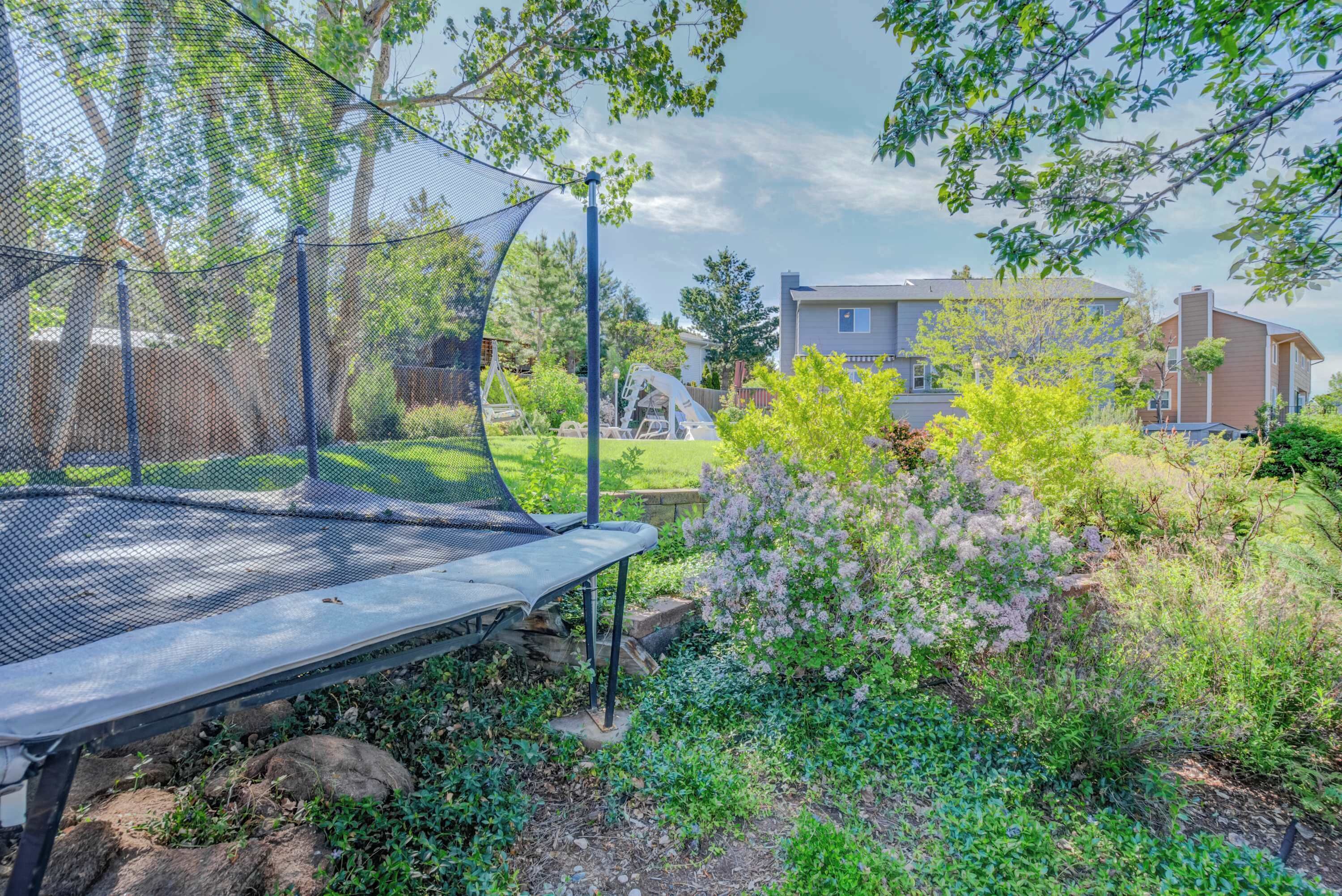 A trampoline in a backyard with a house in the background.