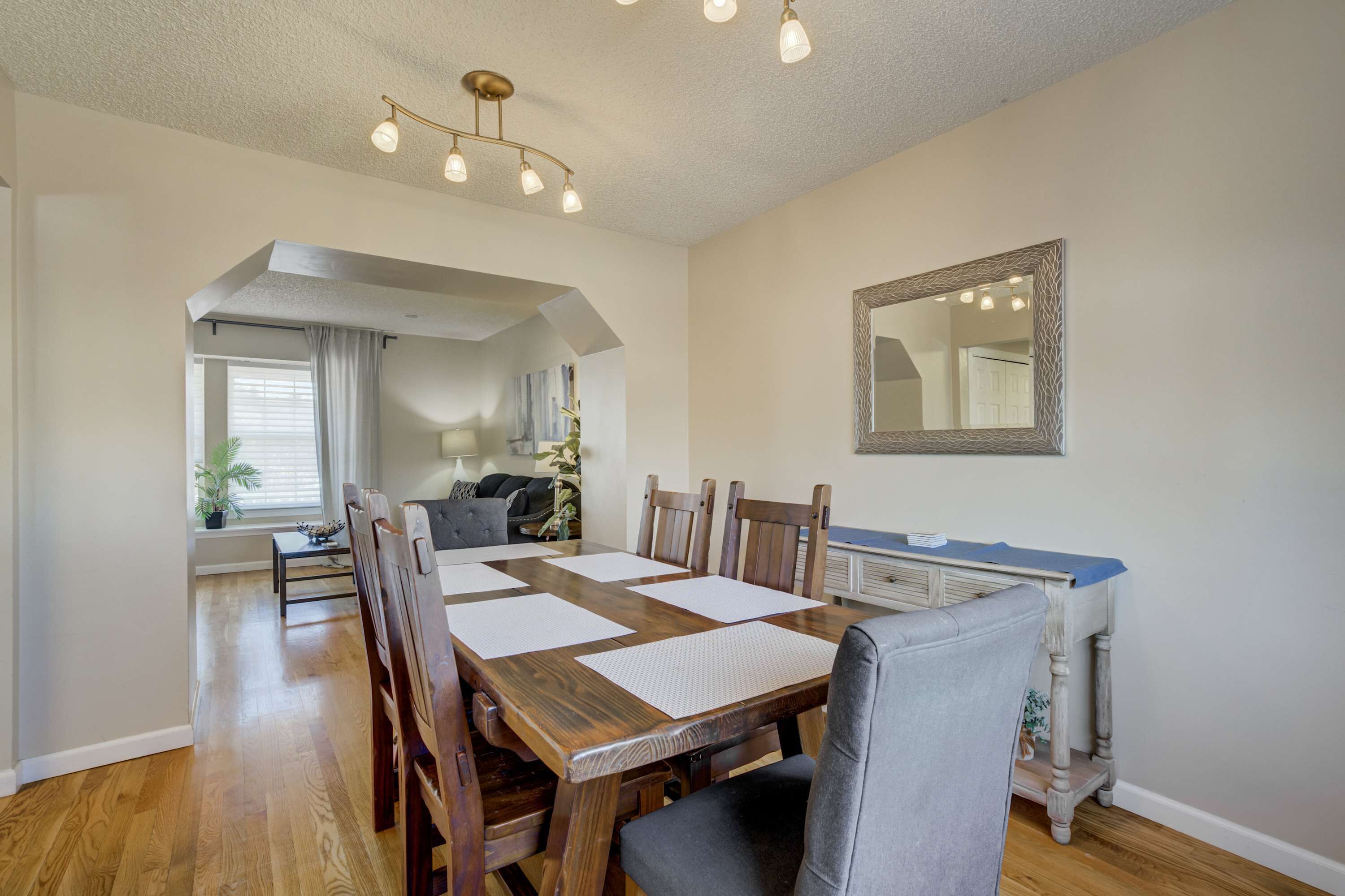 Un coin repas avec une table en bois, des chaises et un miroir au mur.