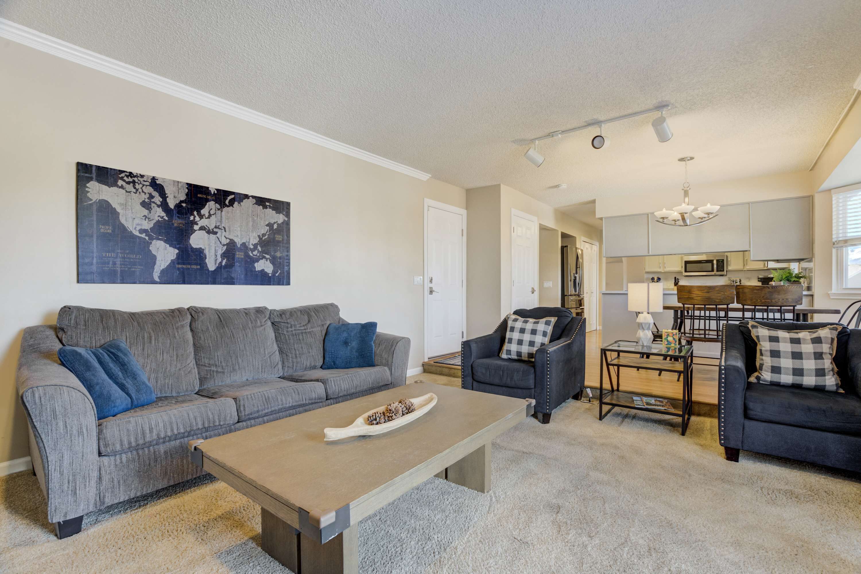 A living room with a grey sofa, a coffee table, and a world map on the wall.