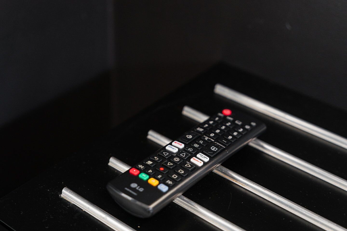 Une télécommande posée sur une surface noire, avec des barres métalliques.