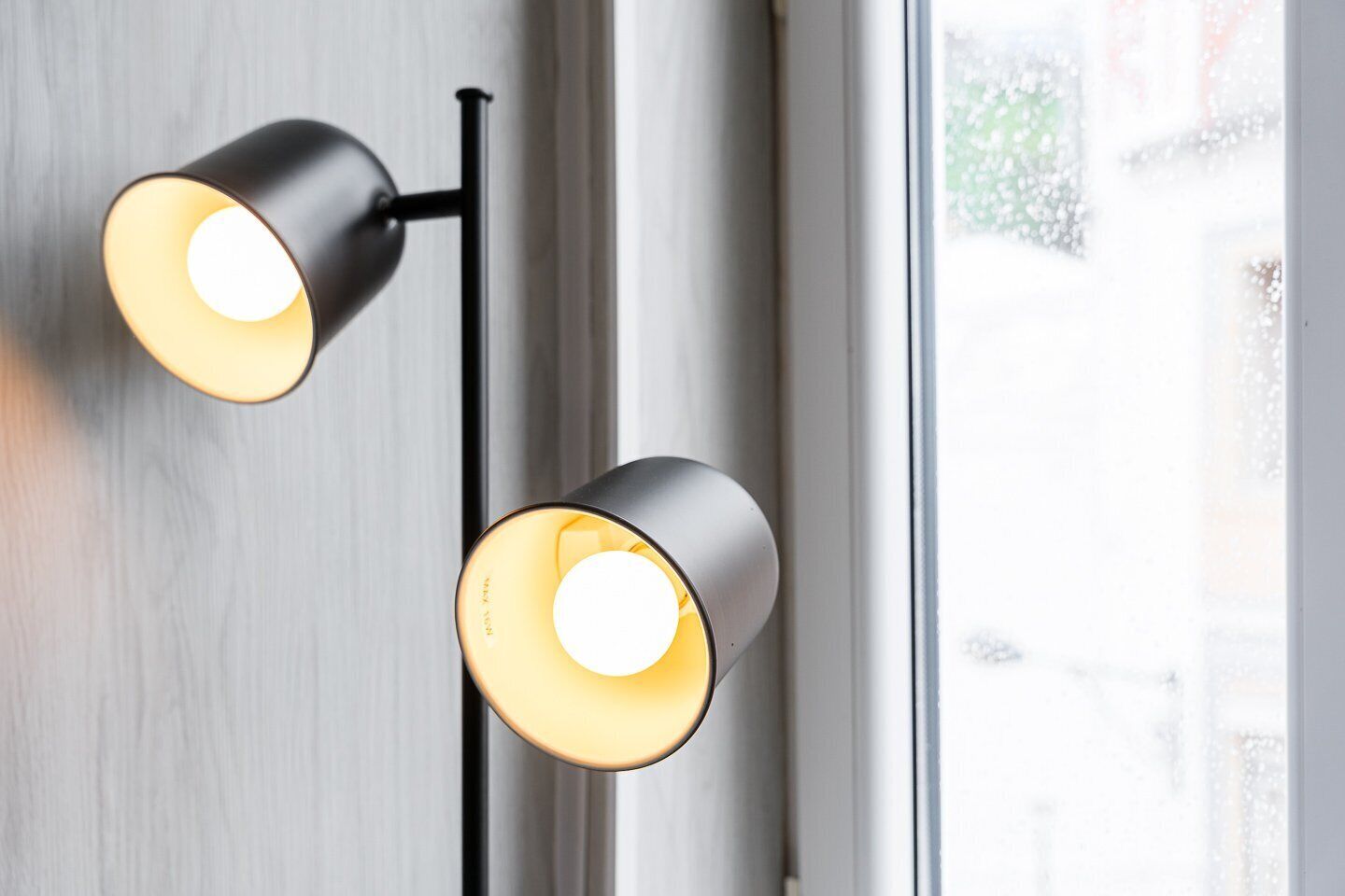 Een moderne lamp met twee bolvormige lampen tegen een witte muur.