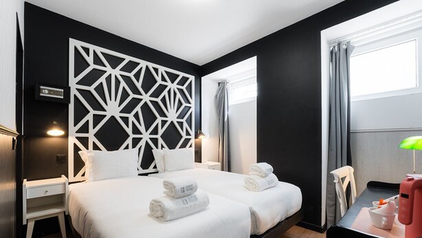 Una habitación de hotel moderna con una cama grande, un escritorio y una silla.