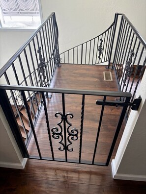 A wooden staircase with black metal railings and a decorative gate. - Movie Theater Retreat With Pickleball Court (Post Falls)