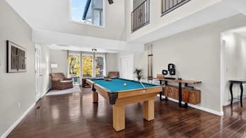 A spacious room with a pool table, a ceiling fan, and a view of the outdoors.