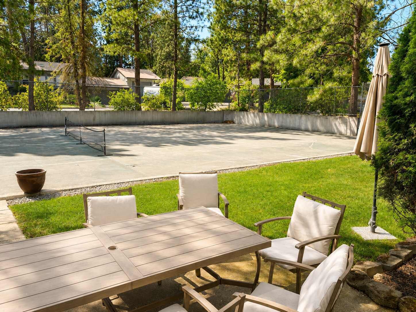 Uma área de pátio com mesa e cadeiras, um espaço de recreação em concreto e um gramado.