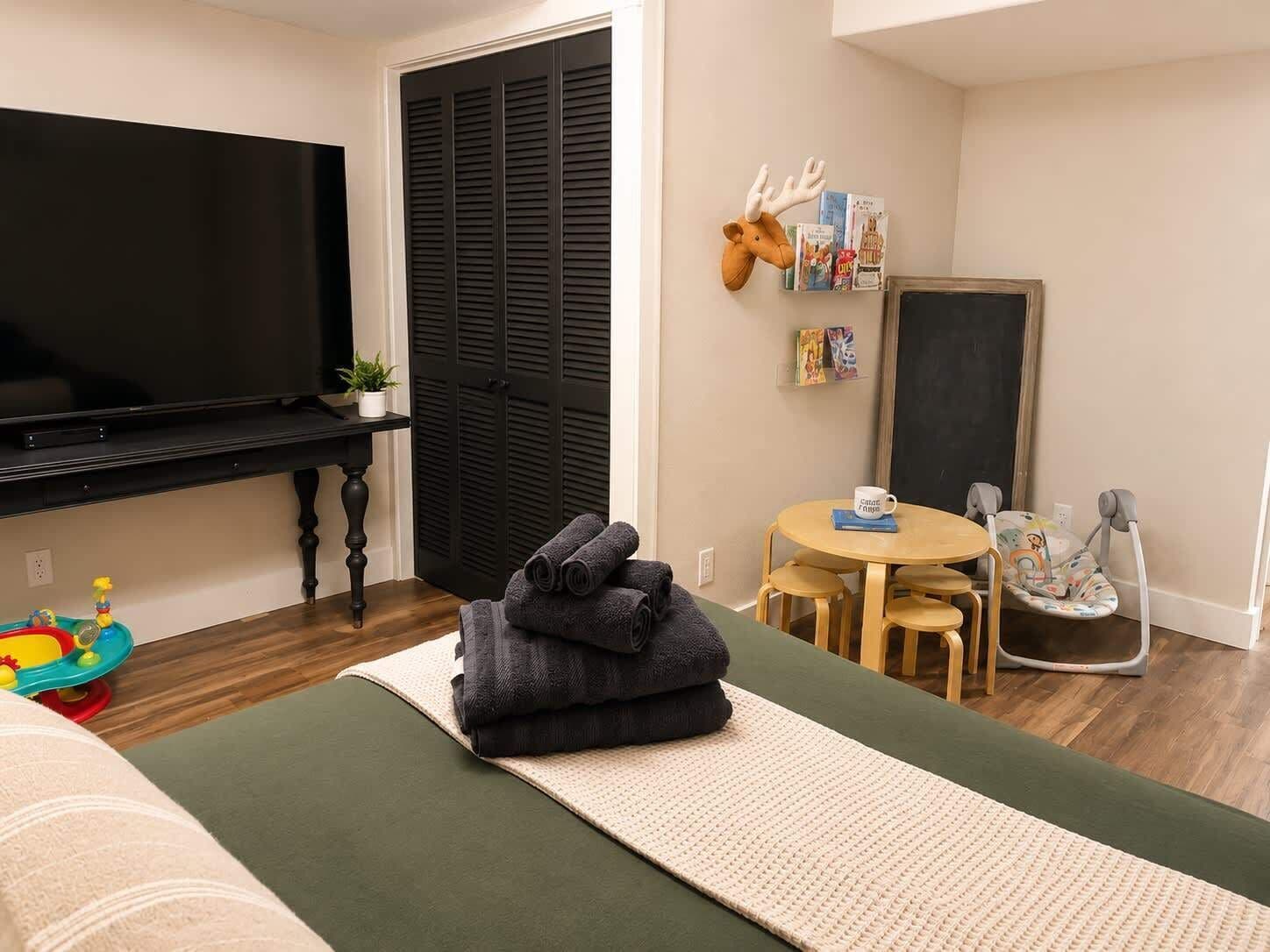 Huge family bedroom with TV, toys, crib, bassinet, and baby swing