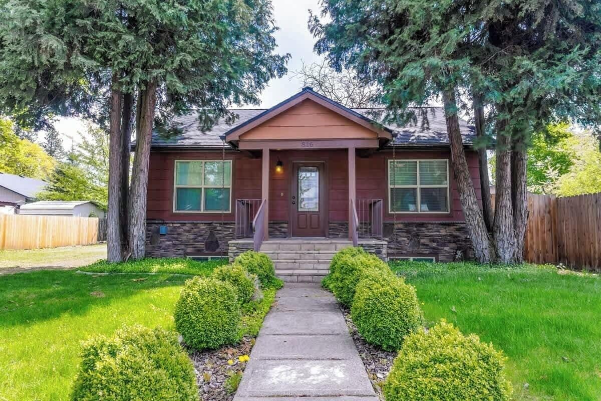 A two-story house with a front porch, a stone foundation, and a well-maintained lawn.