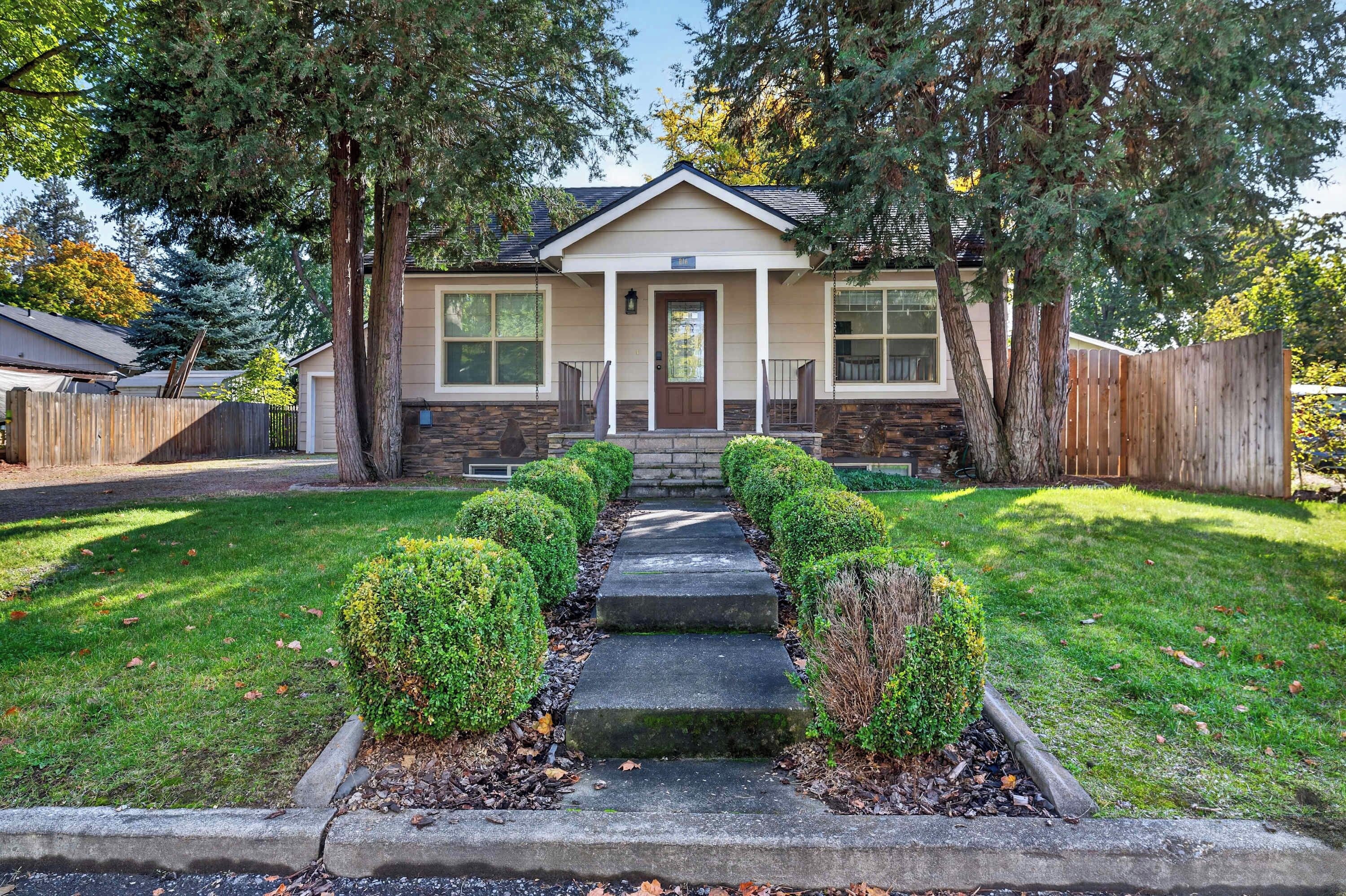 A two-story house with a front porch, stone steps, and a well-maintained lawn.