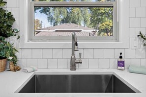 Modern kitchen sink with a sleek faucet  and a window overlooking the greenery.