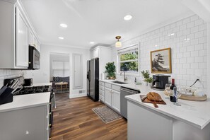 A modern kitchen with white cabinetry, a central island, and a dining area with a sofa and table.