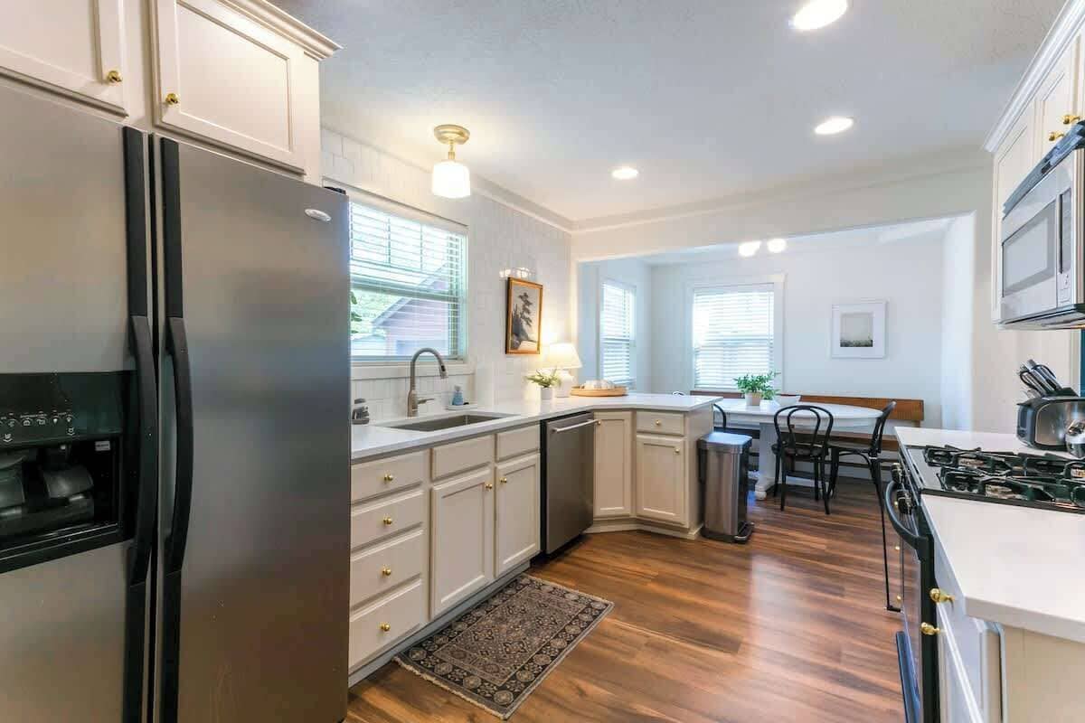 A modern kitchen with white cabinetry, stainless steel appliances, and a central island.