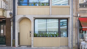 A modern building with a large arched entrance, a balcony with plants, and a large window. - Casa da Música Modern Flat (Porto)