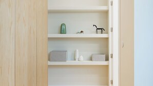 A hallway with wooden flooring, white walls, and shelves with various items. - Casa da Música Modern Flat (Porto)