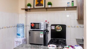 A kitchen with a microwave, a water dispenser, a gas stove, and a water bottle.