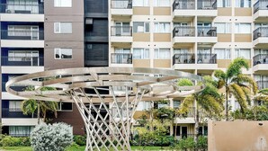 A modern hotel with a central pool area featuring a unique metal sculpture. - Sunset Dreams Studio Haven (Iloilo City)