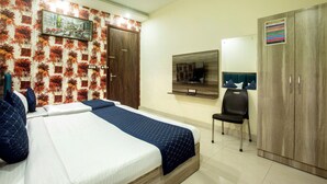 A hotel room with a bed, a desk, a chair, a wardrobe, and a wall-mounted TV. - Hotel Volga Deluxe (New Delhi)