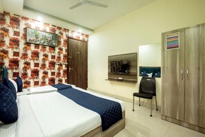 A hotel room with a bed, a desk, a chair, a wardrobe, and a wall-mounted TV.