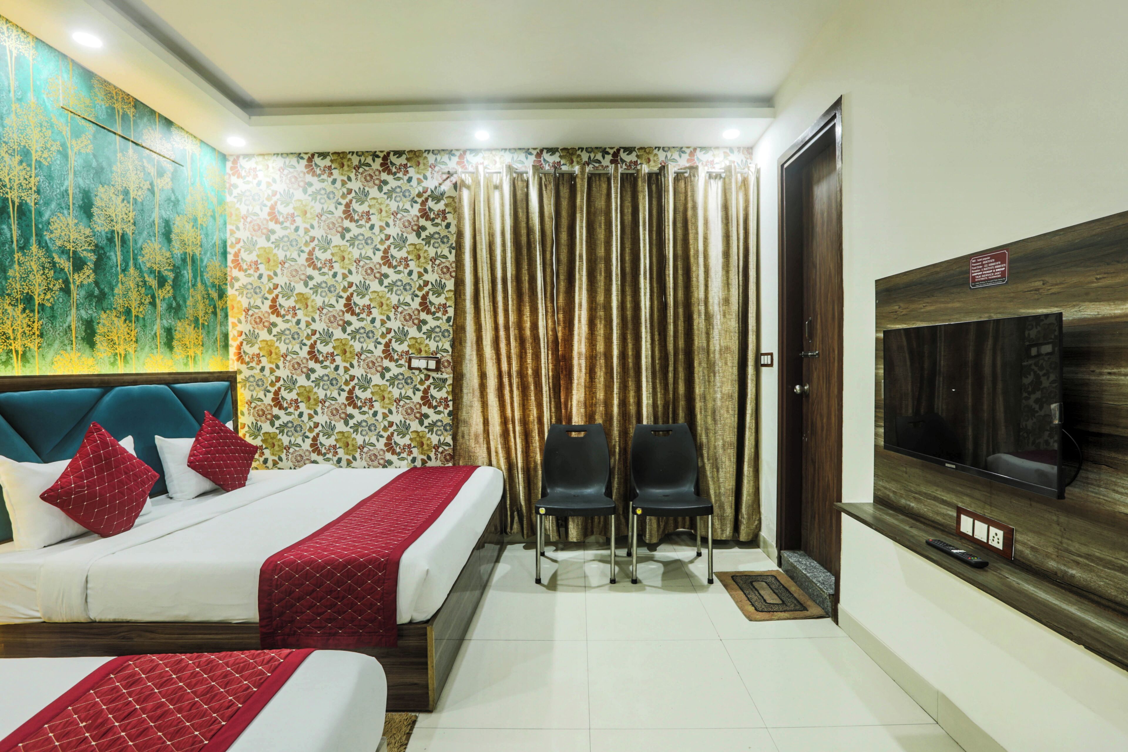 A hotel room with two beds, a TV, and a large window with curtains.
