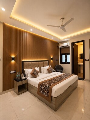 A modern bedroom with a large bed, bedside tables, a ceiling fan, and an air conditioning unit. - Hotel Volga Deluxe (New Delhi)