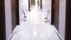 A hallway with doors on both sides, potted plants, and a staircase in the distance. - Hotel Volga Deluxe (New Delhi)