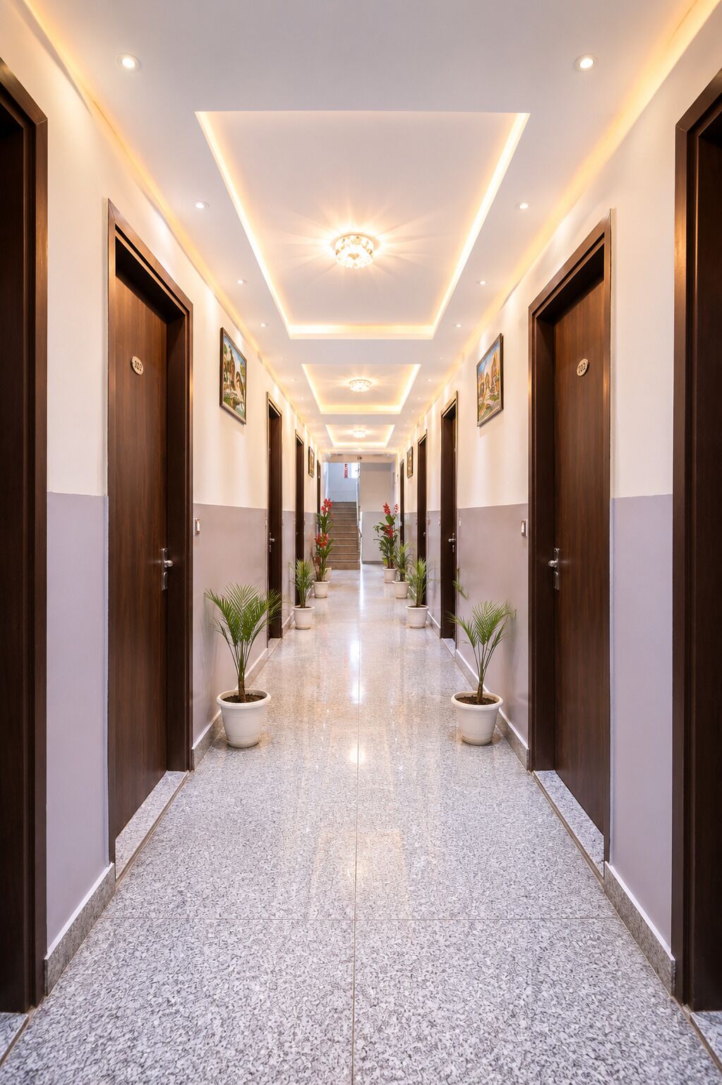 A hotel hallway with a polished marble floor, wooden doors, and potted plants.