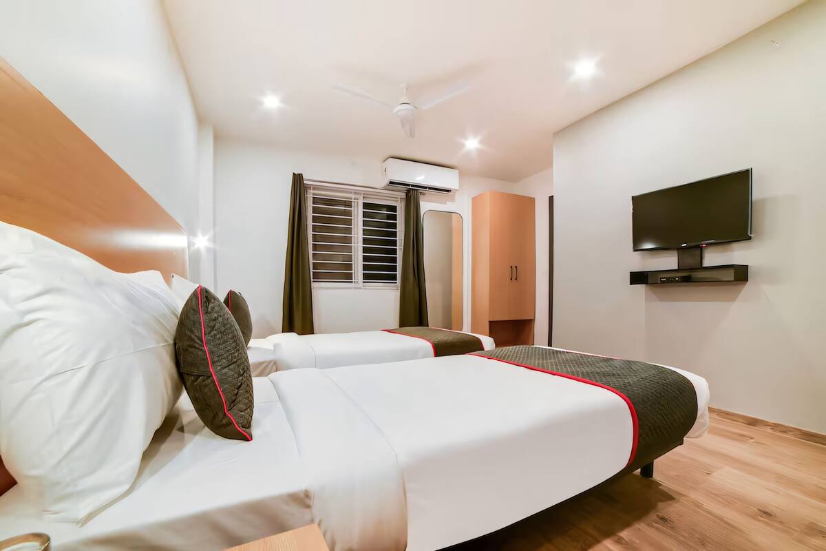 Quarto de hotel com duas camas, uma televisão e um ar condicionado.