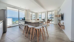 A modern kitchen with a large island, bar stools, and a view of the ocean.