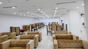 A spacious room with rows of beige upholstered chairs and a polished floor, arranged for seating. - Hotel The Anvi Residency  (Noida)
