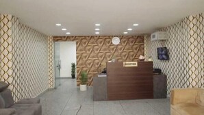 A reception area with a reception desk labeled "RECEPTION," patterned walls, and a tiled floor. - Hotel The Anvi Residency  (Noida)