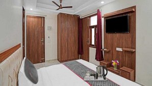 A hotel room with a bed, a ceiling fan, a TV mounted on the wall, and wooden wardrobes. - Hotel The Anvi Residency  (Noida)