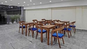 A conference room with wooden tables and chairs, a tiled floor, and recessed ceiling lights. - Hotel The Anvi Residency  (Noida)
