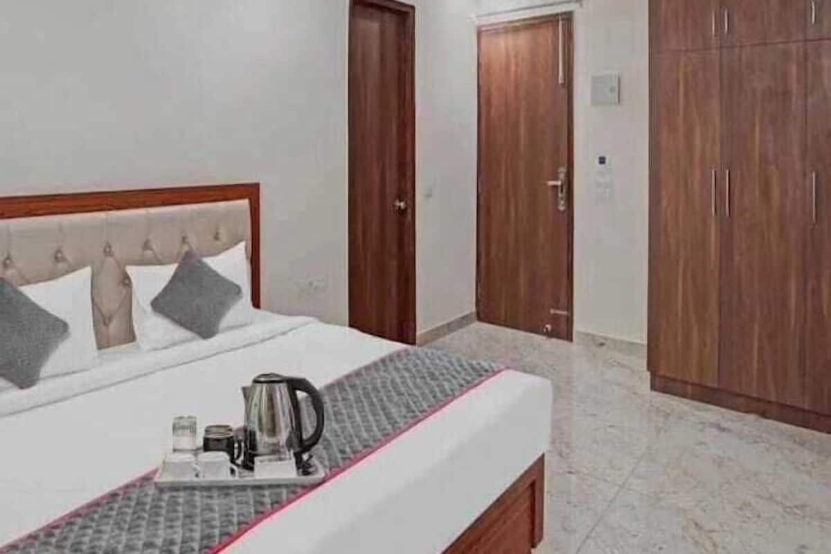 A hotel room with a bed, a ceiling fan, wooden wardrobes, and a coffee maker on the nightstand.