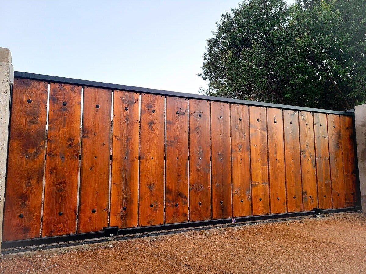 Een lange, houten schutting met gelijkmatig verdeelde verticale planken en een zwarte onderkant.
