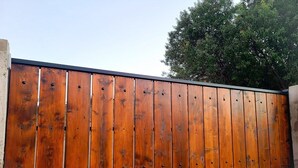 A long, wooden fence with evenly spaced vertical planks and a black bottom edge.
