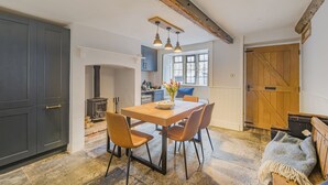 Een eethoek met een houten tafel, vier stoelen en hanglampen.