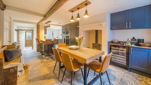Een ruime keuken met een houten eettafel, stoelen en een inbouwoven.