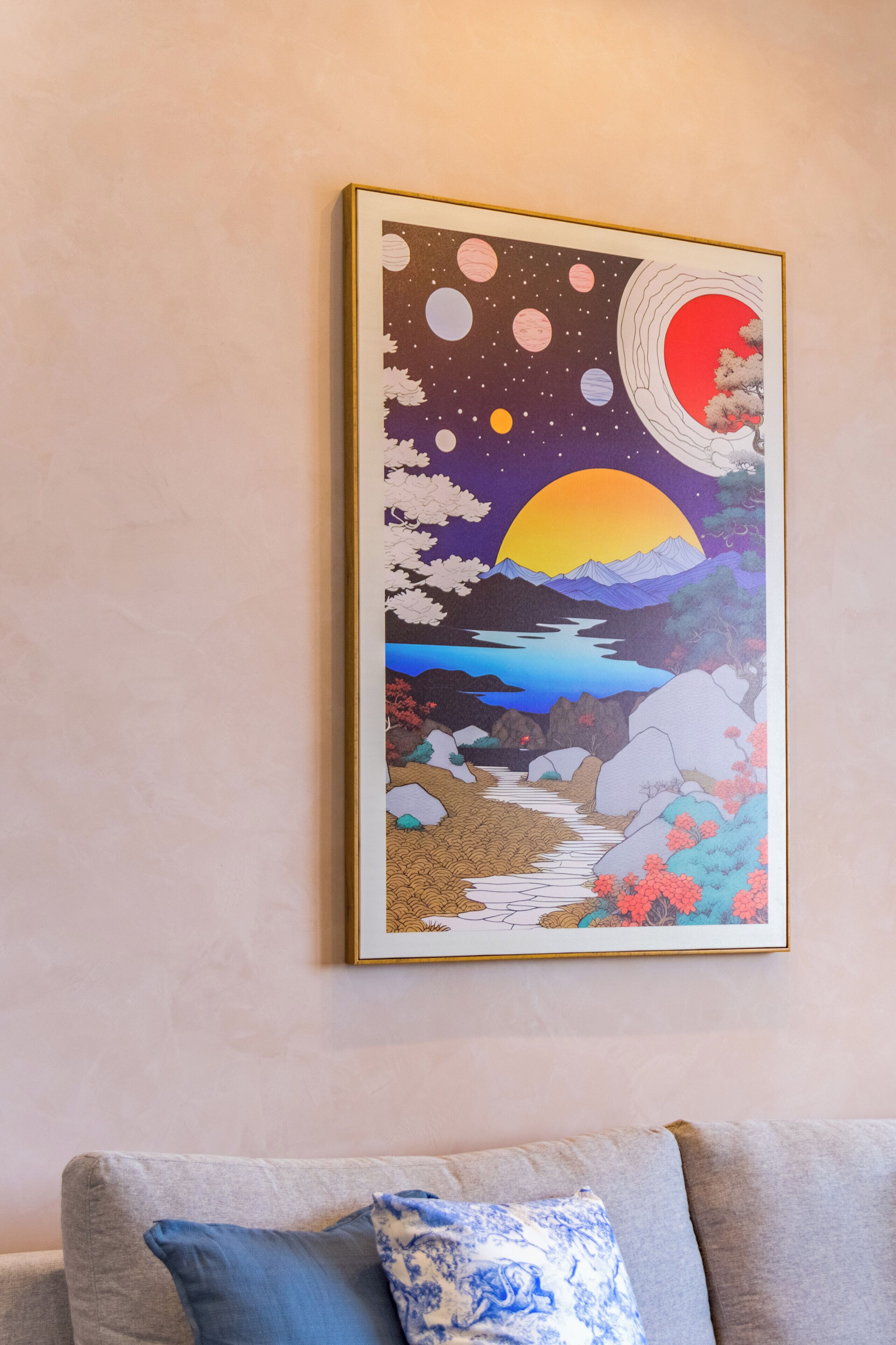 A framed artwork depicting a night scene with a moon, stars, and a sunset over a mountainous landscape with a river.
