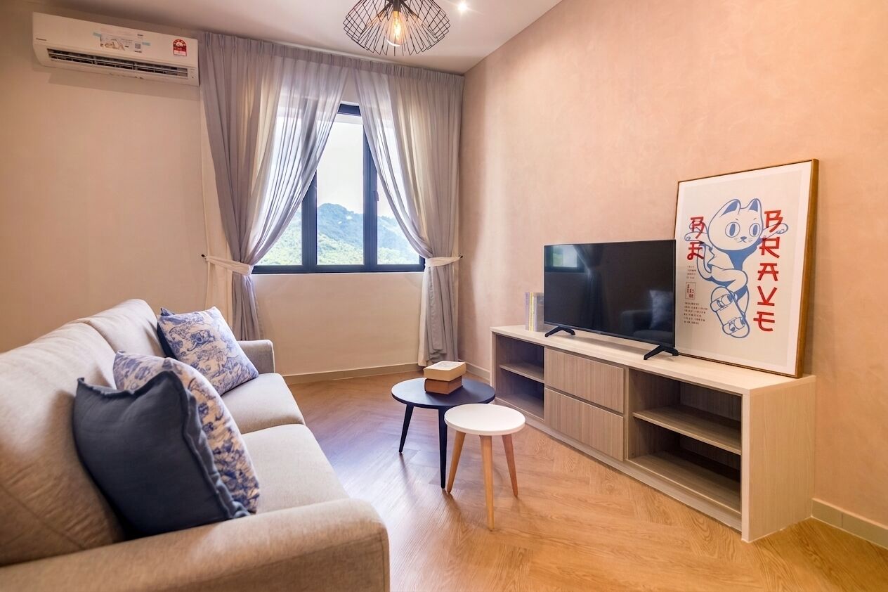 Una sala moderna con un sofá, un televisor de pantalla plana, una mesita y un ventanal con cortinas.