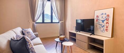 Una sala moderna con un sofá, un televisor de pantalla plana, una mesita y un ventanal con cortinas.