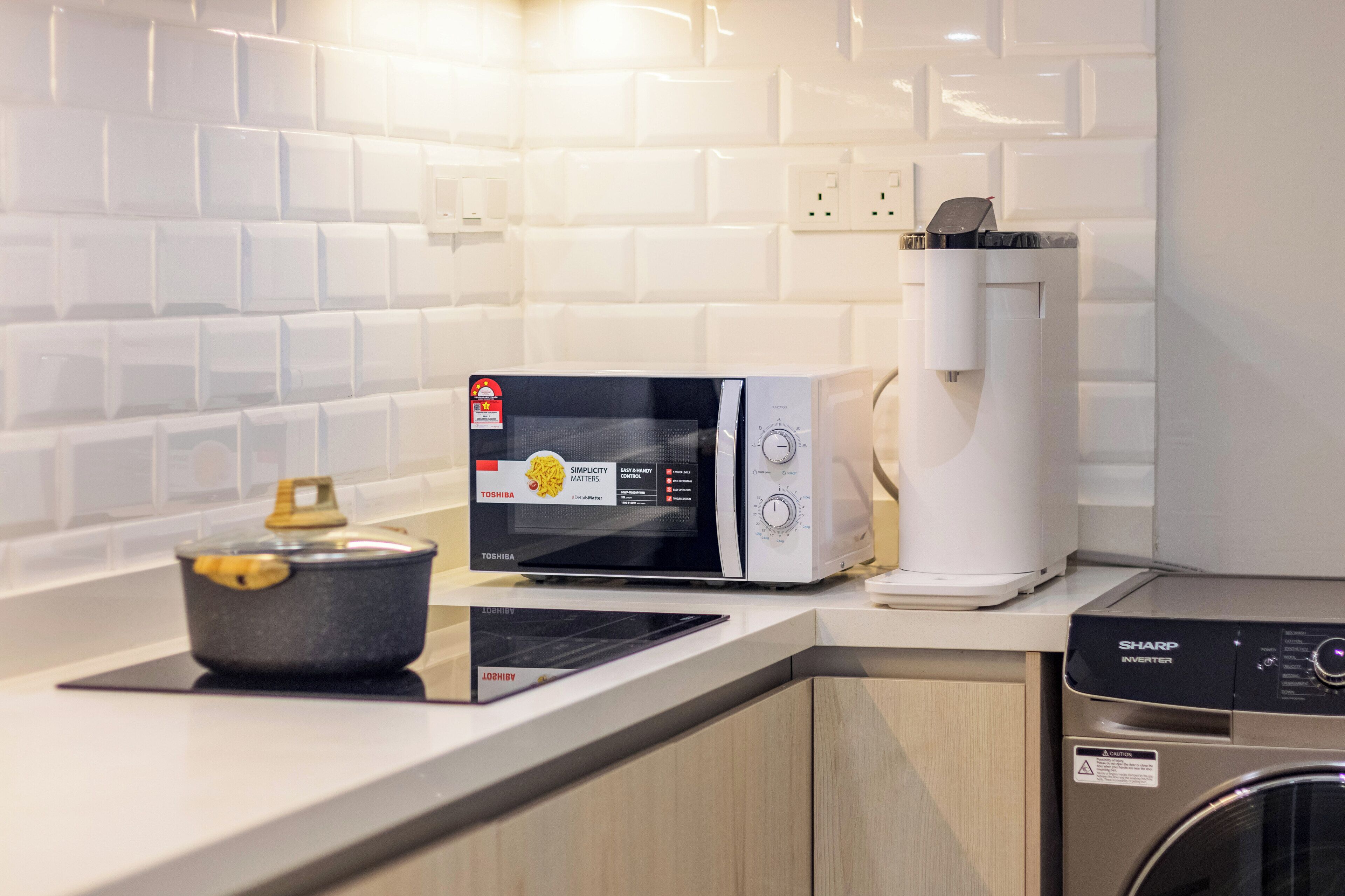 Een keuken met een magnetron, broodrooster en wasmachine.