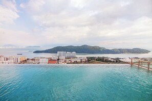 A coastal cityscape with a clear view of the sea, a bridge, and a distant island.