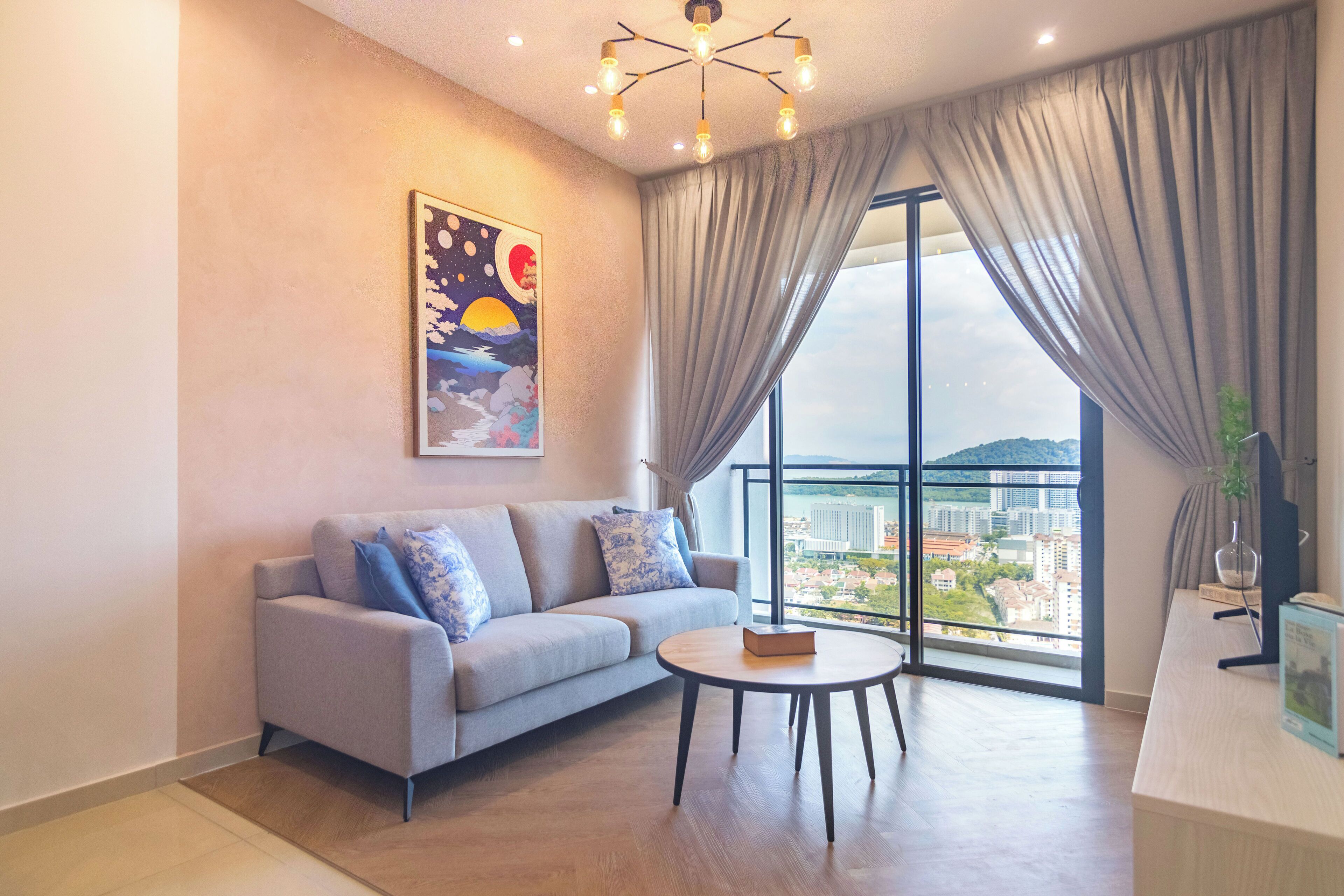 A modern living room with a sofa, a round coffee table, and a large window with curtains.