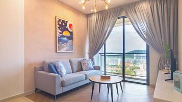 A modern living room with a sofa, a round coffee table, and a large window with curtains.
