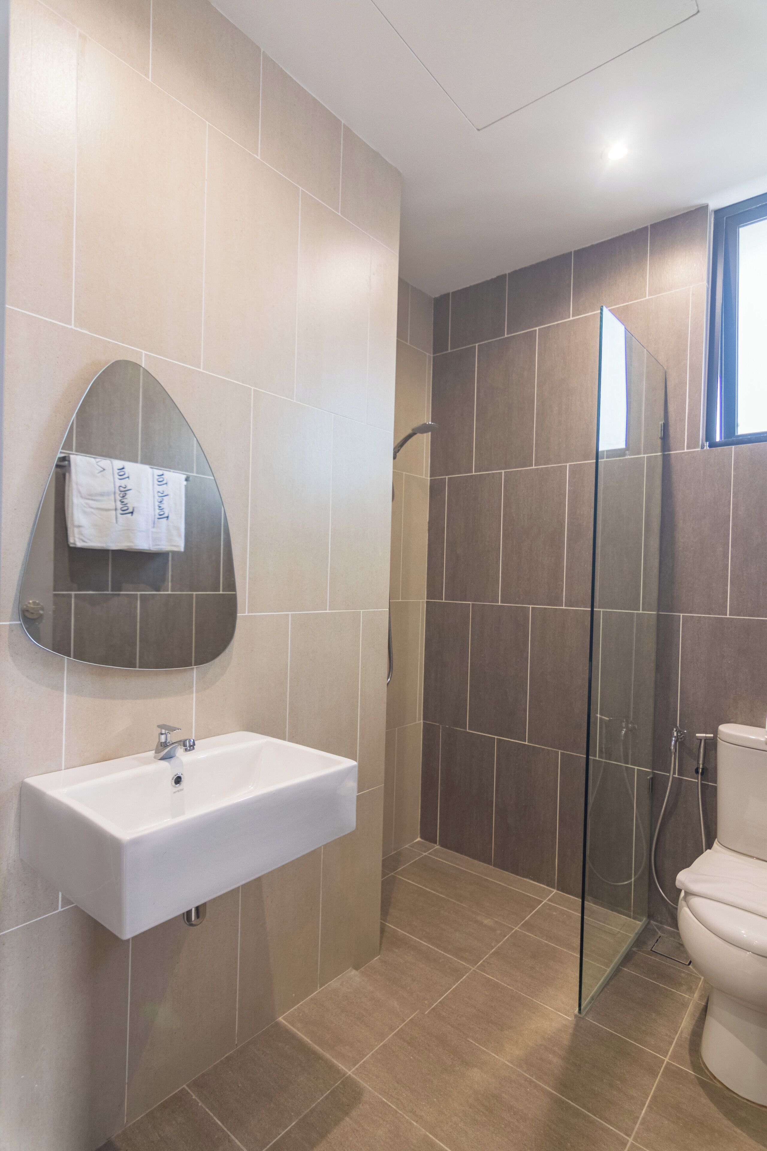 A bathroom with a white sink, a mirror, a shower enclosure, and a toilet.