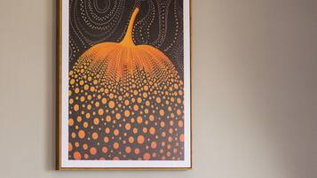 A framed artwork titled 'Pumpkin Forever' on a wall above a grey sofa.