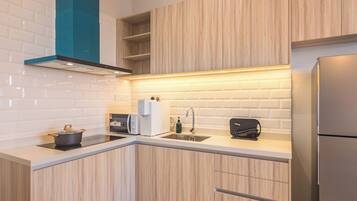 A modern kitchen with wooden cabinets, a built-in oven, a sink, and a stainless steel refrigerator.