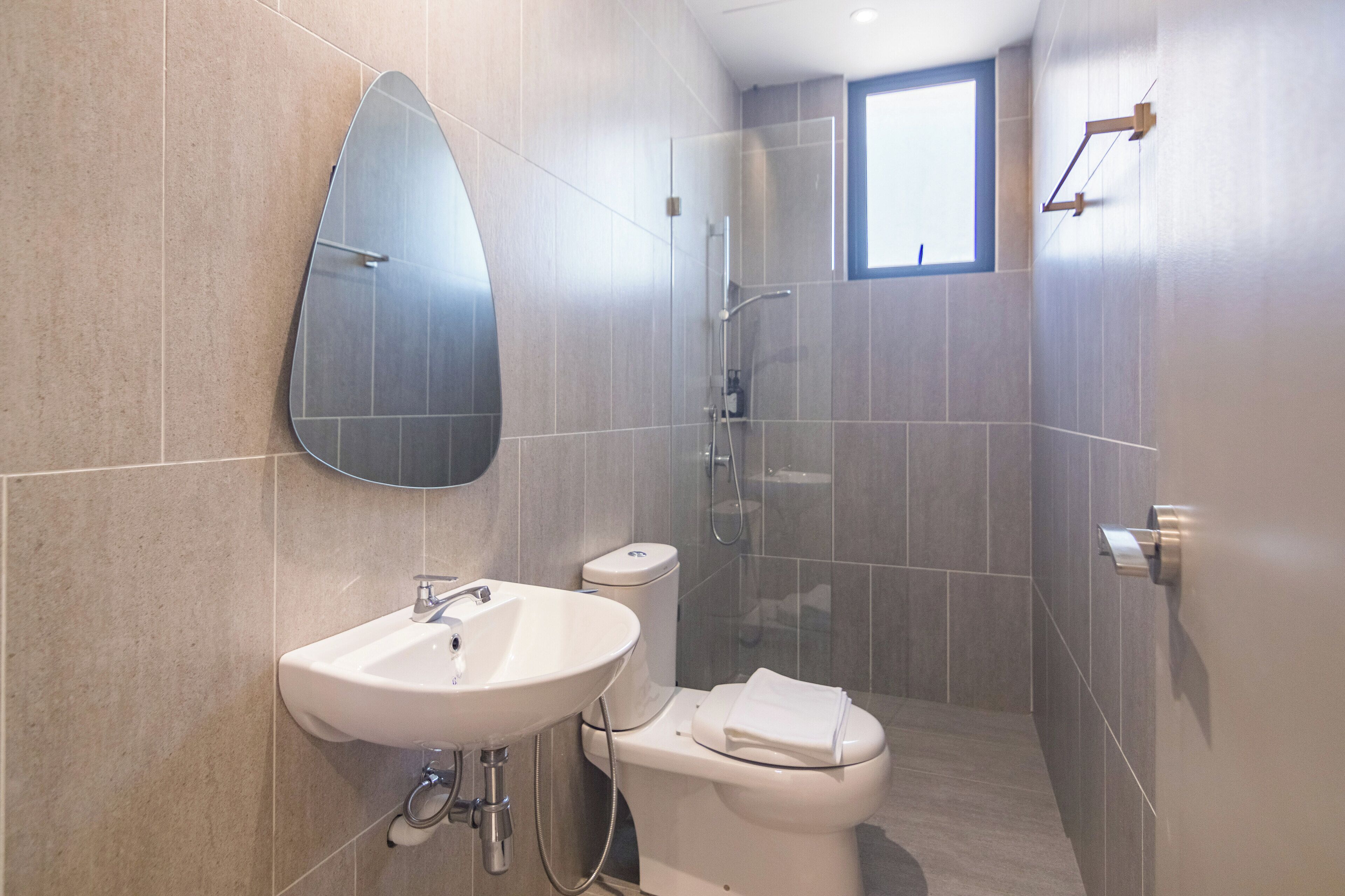 A modern bathroom with a white sink, toilet, and shower.