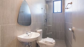 A modern bathroom with a white sink, toilet, and shower.